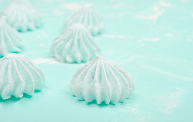 Obraz na płótnie Canvas Freshly baked meringue cookies of mint color (on a light mint background), shallow DOF, selective focus, copy space on the right