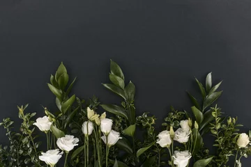 Fotobehang top view of eustoma flowers and branches over black background © LIGHTFIELD STUDIOS