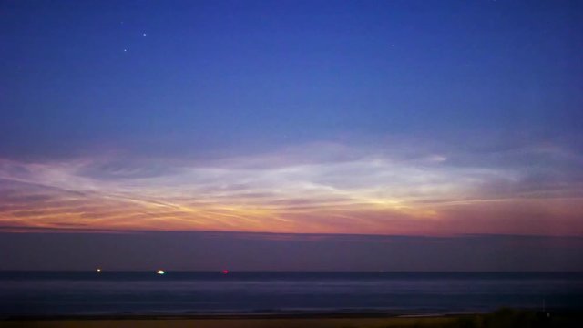 noctilucent clouds NLC over North Sea with ships passing summer midnight twilight timelapse