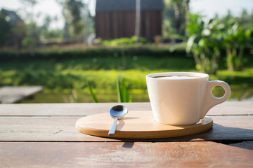 A cup of hot coffee on wooden table in the morning.