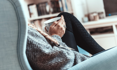 Junge Frau entspannt mit einer Tasse Tee im Sessel