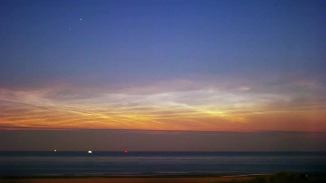 noctilucent clouds NLC over North Sea with ships passing summer midnight twilight timelapse