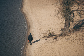 high angle view of man with suitcase walking by sandy beach in autumn