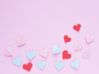 Plakat Pattern of paper origami hearts on a pink background. Valentine's day background. The hearts are blue and pink.