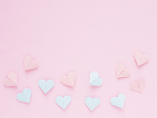 Pattern of paper origami hearts on a pink background. Valentine's day background. The hearts are blue and pink.