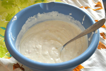 Raw batter and a spoon in a deep blue plastic bowl close-up.