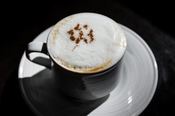 Hot cappuccino on the table with plenty of sunshine.