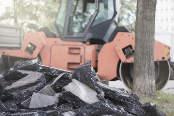 груда кусков вскрытого асфальта на фоне дорожной техники