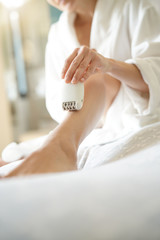 Woman in bedoom shaving legs with electric razor