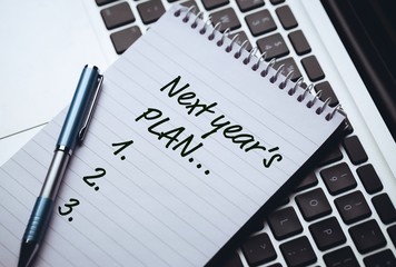 Top View of new years resolution written  on notepad with pen on side laying on laptops keyboard