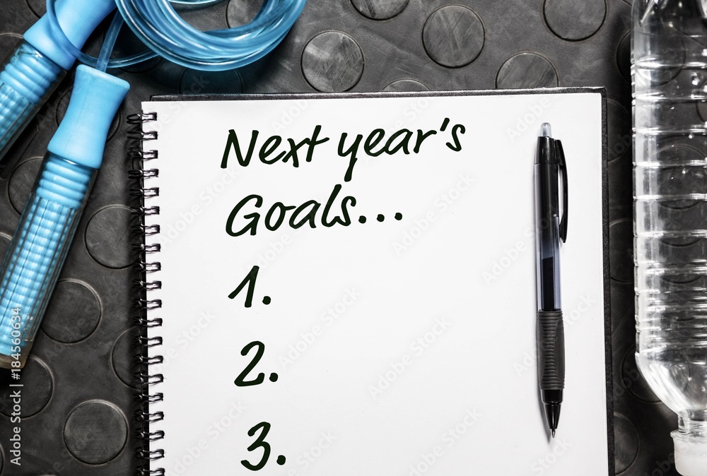 Poster top view of new years resolution written on notepad with pen and skipping rope on side