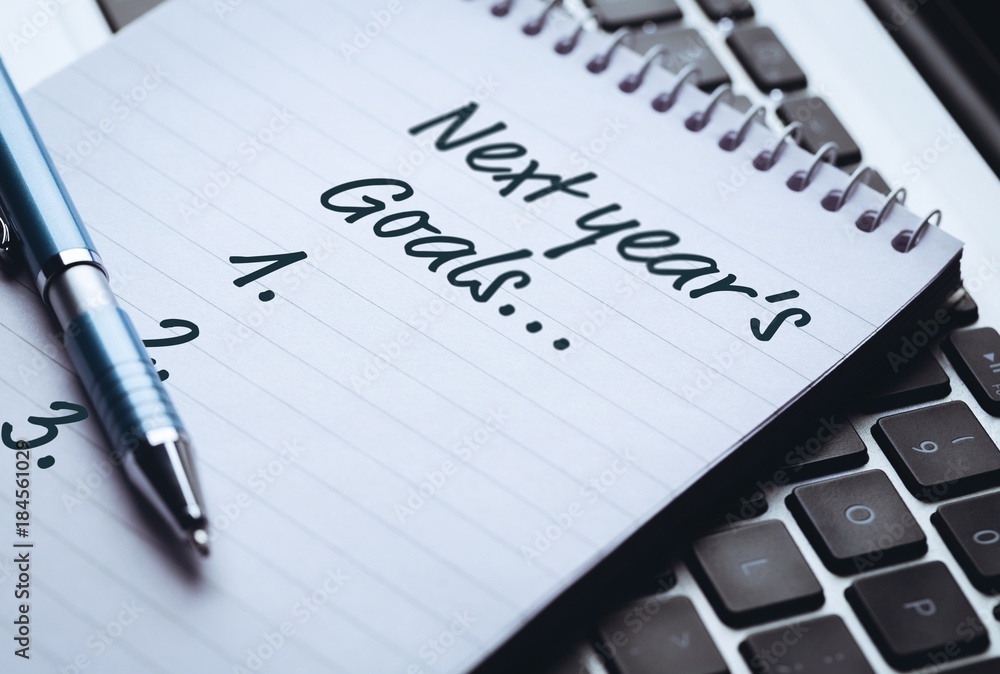 Poster top view of new years resolution written on notepad with pen on side on laptop