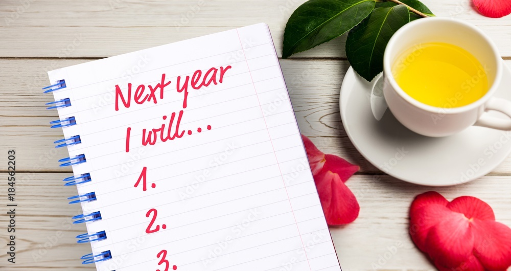 Poster top view of new years resolution list written on notepad with cup of tea