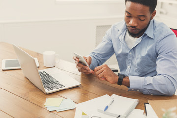 Young black businessman with smartwatch in office