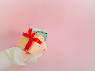 concept for christmas and new year event with beauty hand woman with winter cloth holding gift box and give it to pauper person with isolated pink background