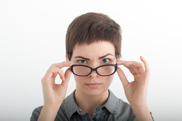 Businesswoman looking sternly over her glasses. Portrait of fashionable brunette woman, looking at camera