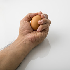 Obraz premium Close up of a Human Hand Holding Brown Egg Isolated on White Background Shot in Studio.