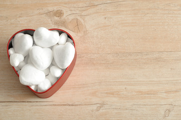 Valentine's Day. A red heart shape tin filled with with polystyrene hearts