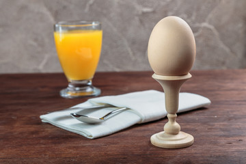 chicken cooked soft-boiled egg on turned wooden stand with orange juice is served on the table