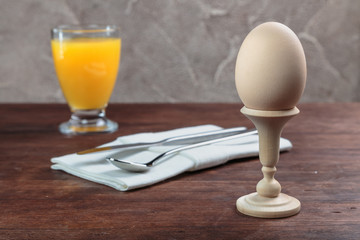 chicken cooked soft-boiled egg on turned wooden stand with orange juice is served on the table
