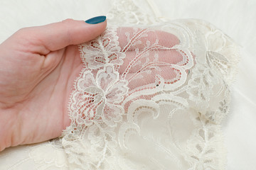 Part white lace wear in a female hand. Fashionable concept. Close up