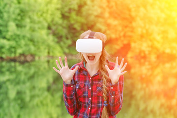 Girl in a helmet of virtual reality on a background of nature. Fright