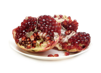 Separated pomegranate with ripe seeds on a plate isolated on white background front view closeup