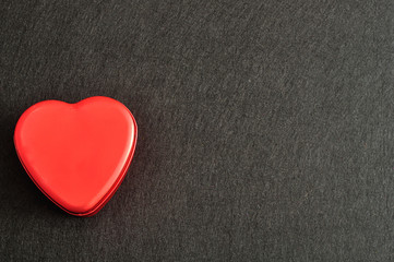 Obraz premium Valentine's Day. A red heart shape tin isolated on a black background