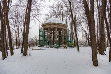 Repair work at an abandoned stone rotunda in a winter park

