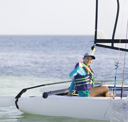 Beautiful teenager sailing catamaran in beautiful sunset.