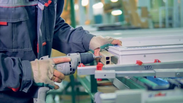 Worker manufacturing plastic window. Assembly line of PVC windows and doors.