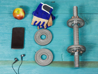 Sport items bottle, dumbbells, gloves on the sport flooring