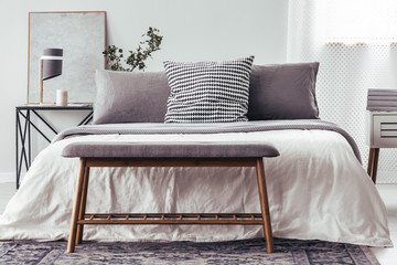 Wooden bench against white bed