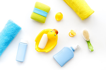 Bath accessories for kids. Yellow rubber duck, soap, sponge, brushes, towel on white background top view