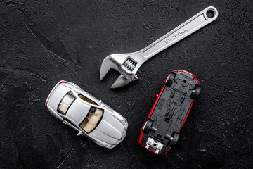 Car repair concept. Wrench near car toys on black background top view