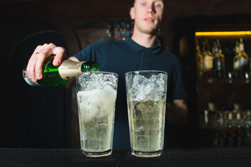 Creating a beautiful alcoholic cocktail. A barman pours alcohol from a bottle into a glass for a cocktail.