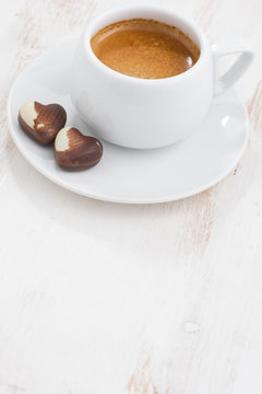 chocolate hearts and espresso on white wooden background, top view, vertical