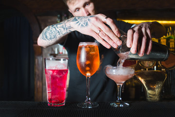 A barman pours mixed alcohol from a shaker into a glass. Creation of beautiful alcoholic cocktails. Nice alcohol.