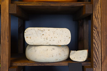 Hard cheese in wheel and piece on grocery shop shelf
