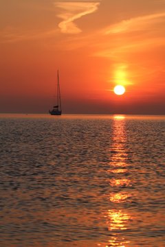 malerischer Sonnenaufgang am Meer, Boot am Horizont, Seebestattung