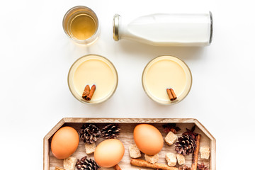 Make eggnog classic recipe. Eggs, milk, cinnamon, whiskey on white background top view