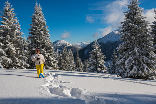 Joyful woman, traveler goes snowshoeing in deep snow