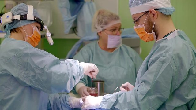 two plastic surgeons are performing rhinoplasty operation for correcting and reconstructing form of human nose