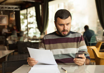 Shocked man checking his mobile phone