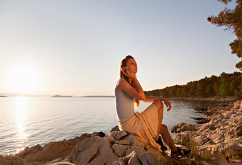 Woman listening to shell at beach © Image Source RF