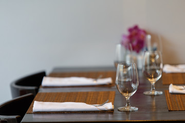 Dining table with spoon, knife and glass, with napkin and dish plate on the dining table.