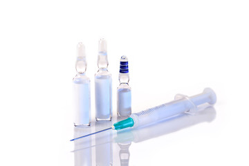 three ampoules and a lying syringe isolated on a white background