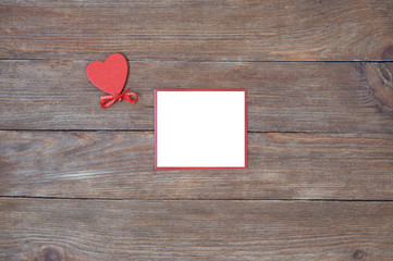 Valentine's Day. Red heart with ribbon and message card on a wooden background.