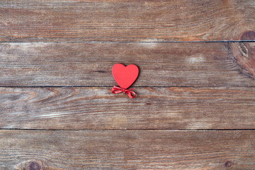 Valentine's Day. Red heart with ribbon on a wooden background.