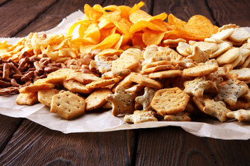 Salty snacks. Pretzels, chips, crackers on brown wooden backgroun d